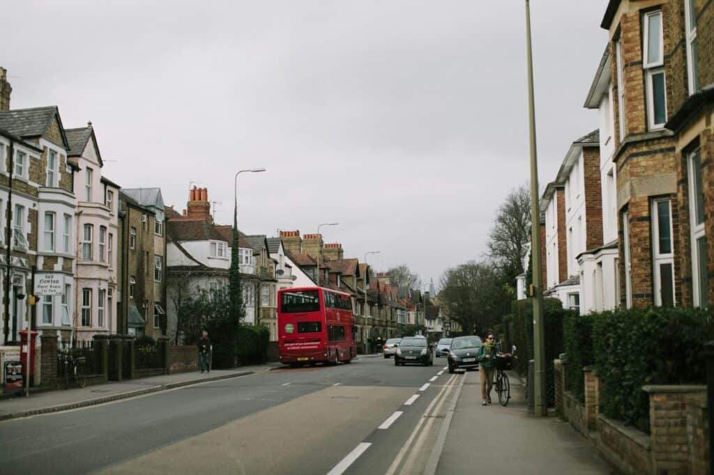 A red bus on a street surrounded by rows of residential buildings