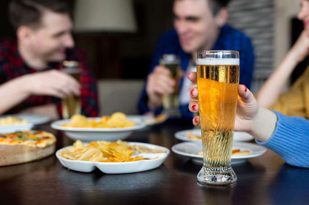 Friends dining in a pub with food and glasses of beer on the table