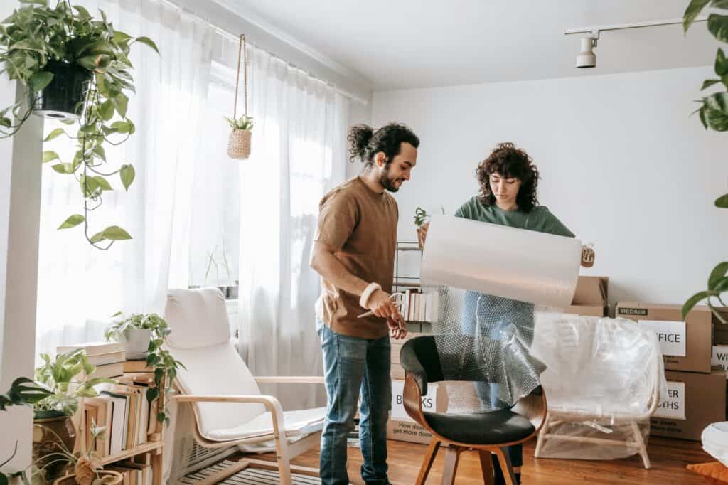 A couple is wrapping chairs for their house move