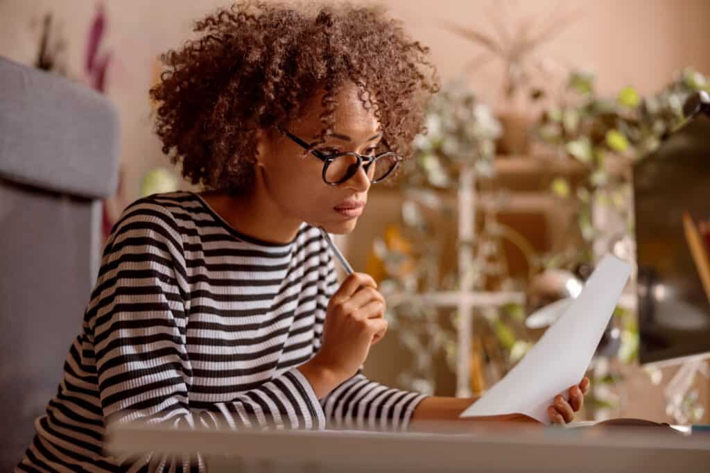 A woman planning a budget for the move: holding a paper in front of the computer