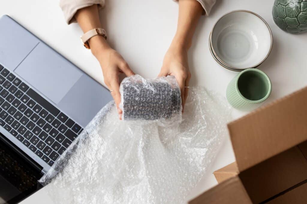 Cropped image of a woman protecting a ceramic with bubble wrap for the move