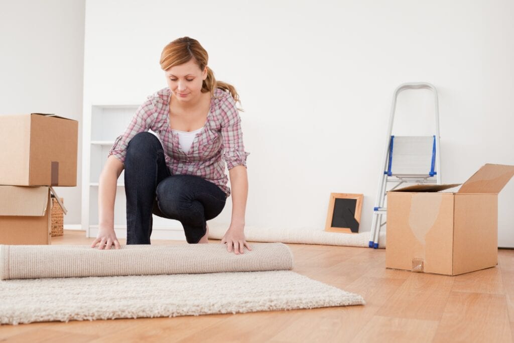 A young lady rolling up the carpet for the move